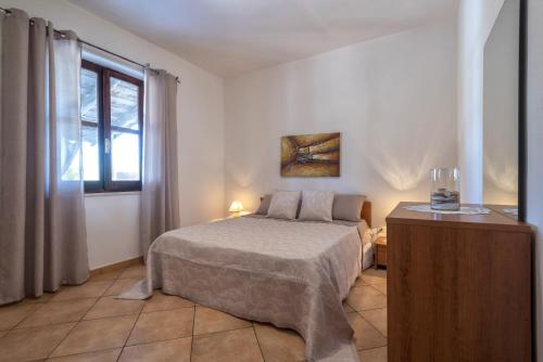 a white bedroom with a bed and a window at Casa Vacanza da Albino in Sorso