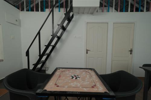 a ping pong table in a room with stairs at Babu's Homestay By Lexstays in Mananthavady