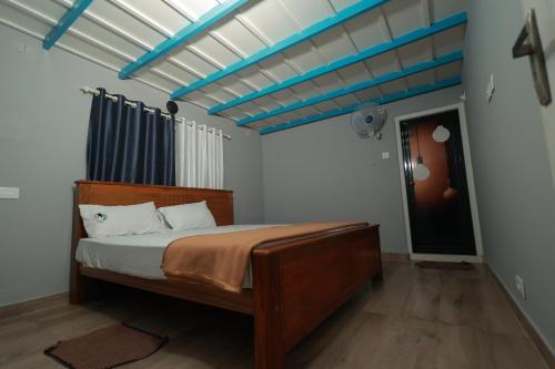 a bedroom with a wooden bed with a blue ceiling at Babu's Homestay By Lexstays in Mananthavady