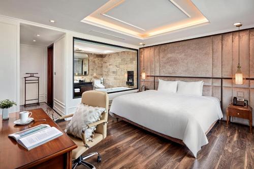 a bedroom with a large white bed and a desk and a desk at Ravatel Luxury Hotel Bac Giang in Bắc Giang