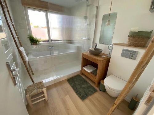een badkamer met een bad, een toilet en een wastafel bij Le dodo mauricien in Wimereux