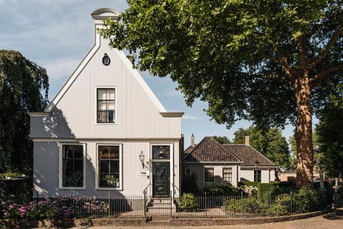 a white house with a tree and flowers at Inn on the Lake in Broek in Waterland