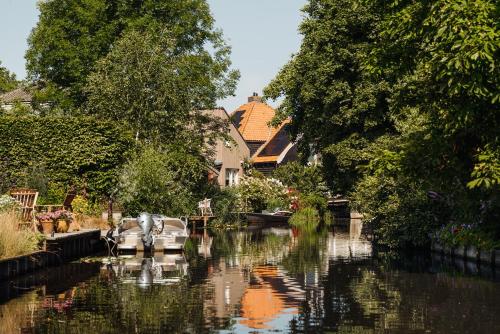 a boat is docked on a river with houses at Inn on the Lake in Broek in Waterland