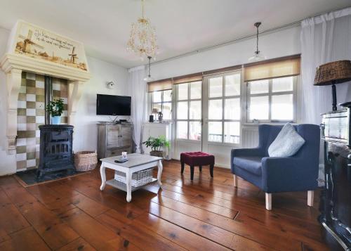 a living room with a blue chair and a fireplace at Idyllisch en knus huisje met prachtige veranda. in Oterleek