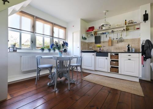 een keuken met witte kasten en een tafel en stoelen bij Idyllisch en knus huisje met prachtige veranda. in Oterleek