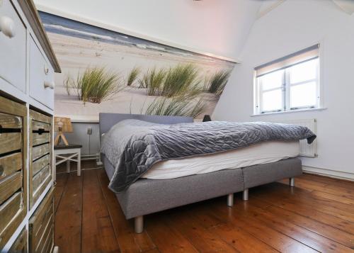 a bedroom with a bed with a painting on the wall at Idyllisch en knus huisje met prachtige veranda. in Oterleek