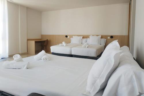 two beds in a hotel room with white sheets at Iraipe Logroño Hotel in Logroño