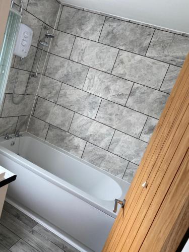 uma banheira na casa de banho com piso em azulejo em lovely4 bedroom house close to Loughborough uni/M1 em Loughborough