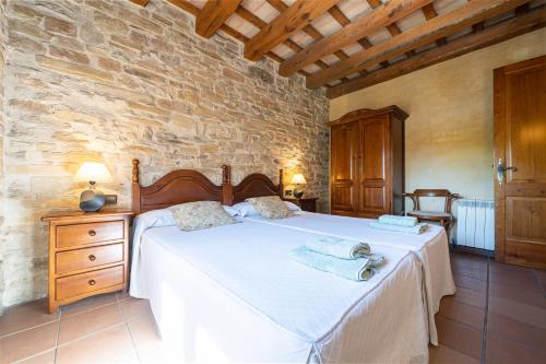 1 dormitorio con cama y pared de piedra en El Clos 2, en Conesa