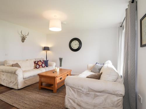 a living room with two couches and a clock on the wall at 6 Bynack More in Aviemore