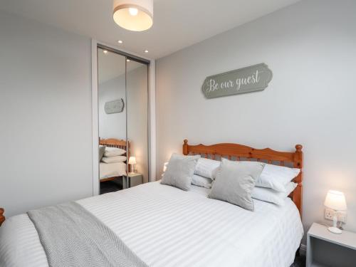 a bedroom with a white bed and a sign on the wall at 6 Bynack More in Aviemore