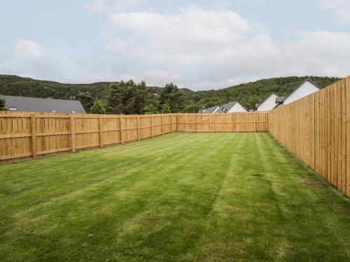 a wooden fence in a yard with a green lawn at 6 Bynack More in Aviemore