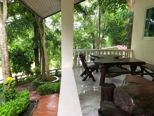a patio with a table and chairs and trees at Saiyok River House in Sai Yok