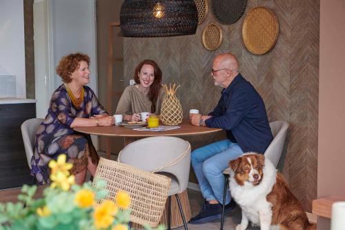 a group of people sitting at a table with a dog at Parc Maasresidence Thorn Apartments in Thorn