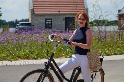 a woman is riding a bike on the street at Parc Maasresidence Thorn Apartments in Thorn