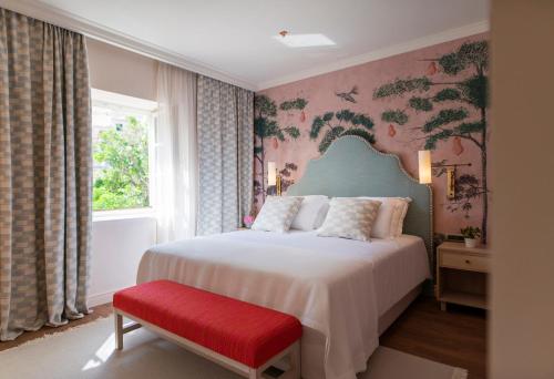 a bedroom with a bed and a red bench at Hotel Supetar in Cavtat