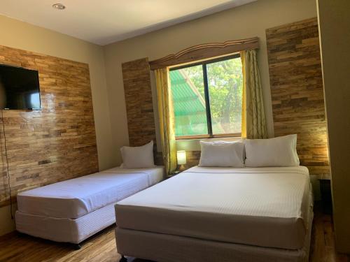 two beds in a room with a window at Mabini Hotel in Mambajao