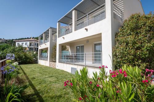 a white house with a yard with flowers at Résidence U Manellu in Santa-Reparata-di-Balagna