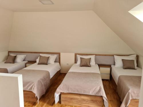 three beds in a room with white walls and wooden floors at Monix Palace Zlatibor in Zlatibor