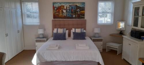 a bedroom with a large white bed with blue pillows at Erinvale Garden cottage in Somerset West