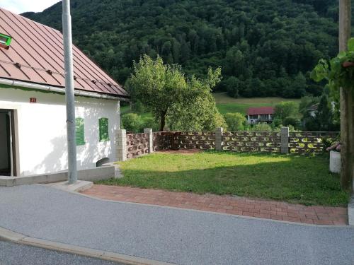 Ein Zaun neben einem weißen Gebäude mit einem Hof in der Unterkunft počitniška hiška MEDVEJKE in Slap ob Idrijci