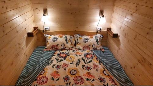 Ce lit se trouve dans une chambre en bois dotée de 2 oreillers. dans l'établissement Tiny house Casa Axa, à Pîrîu Cîrjei