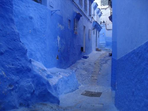 an alley way with blue painted buildings andphalt at Dar Lbakal in Chefchaouene