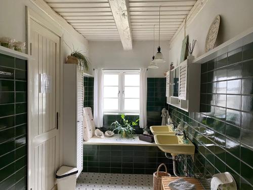 ein grün gefliestes Bad mit einem Waschbecken und einem Fenster in der Unterkunft Heddahgaarden in Bredal