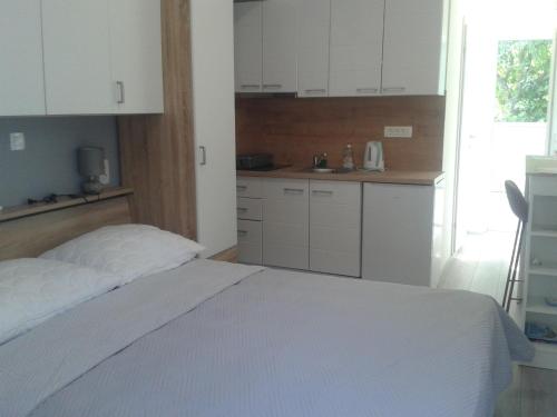 a bedroom with a white bed and a kitchen at Studio Antonio New in Zadar