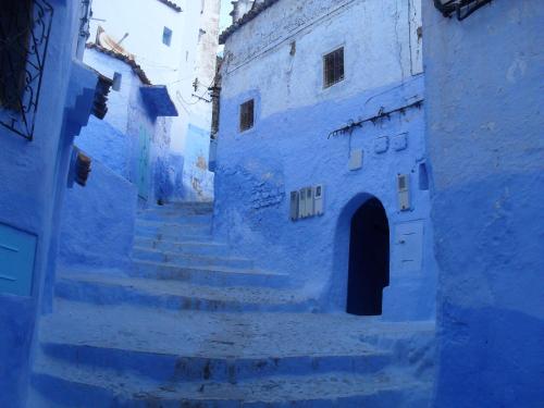 an alley with blue walls and stairs in a town at Dar Lbakal in Chefchaouene