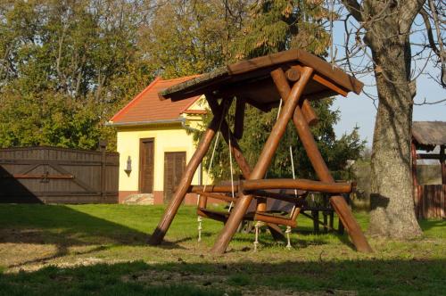 a wooden swing set in a yard next to a tree at Antiklak in Doboz
