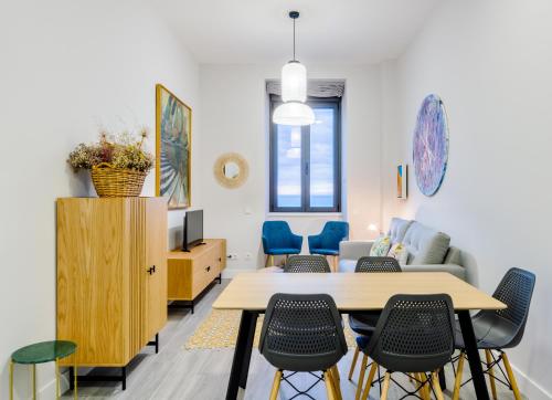 ein Wohnzimmer mit einem Tisch und Stühlen in der Unterkunft Apartamentos La Xiuca Playa in Gijón