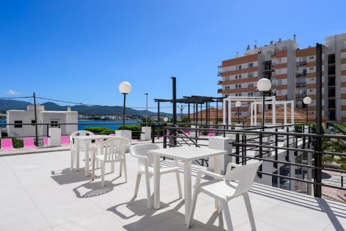 un patio avec des tables et des chaises blanches sur le toit dans l'établissement Aparthotel Vibra Sanan - Adults only, à Sant Antoni de Portmany