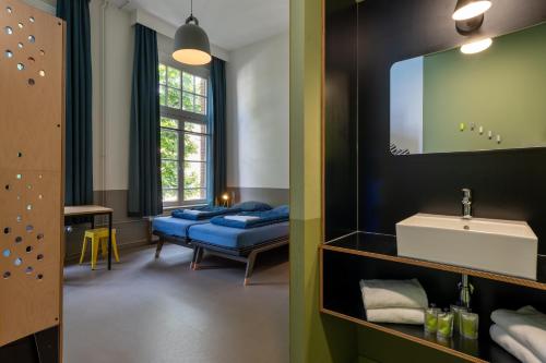 a bathroom with a bed and a sink and a mirror at Stayokay Hostel Amsterdam Vondelpark in Amsterdam