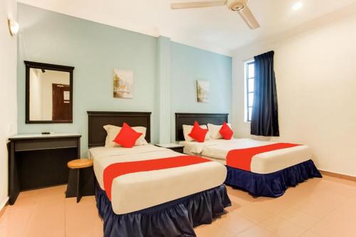 a hotel room with two beds with red pillows at Hotel Home 88 in Teluk Intan