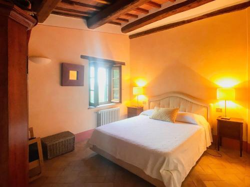 チェトーナにあるLa Terrazza, historic Tuscan stone residence with garden and terrace in Cetonaの白いベッドと窓のある寝室