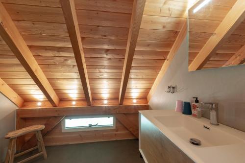 een badkamer met houten plafonds, een wastafel en een raam bij Langevliet 4 - Klaver 4 Callantsoog in Callantsoog