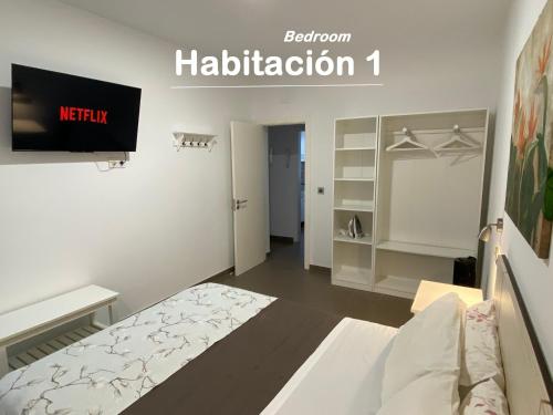 1 dormitorio con 1 cama y TV de pantalla plana en Turina House - 3 habitaciones, en Las Palmas de Gran Canaria