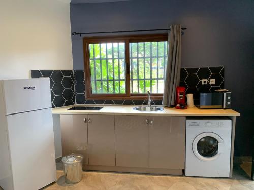 a kitchen with a sink and a washing machine at LE JACQUIER Appartements neufs vue mer ou jardin à Mamoudzou Hyper Centre in Mamoudzou
