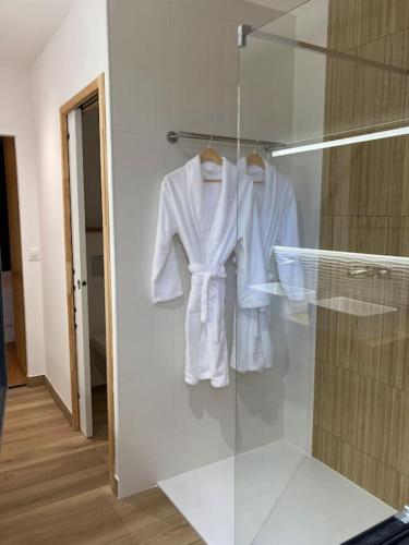 Un peignoir blanc est suspendu dans un placard en verre. dans l'établissement Lodge La Courrège, à Larché
