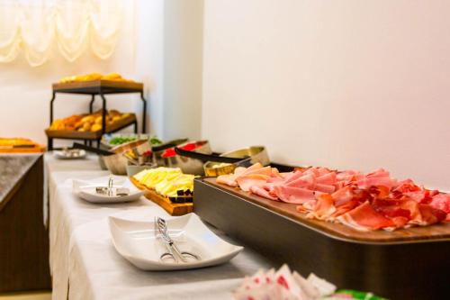 a buffet line with meats and other foods on a table at Hotel Petit Palais in Venice-Lido