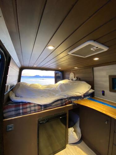 a bed in the middle of a room with a window at Campervan in the Lofoten Islands in Leknes