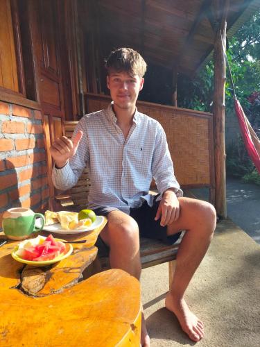 a man sitting on a bench with a bowl of fruit at Friendly Homestay Lemukih in Singaraja