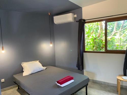 ein kleines Schlafzimmer mit einem Bett und einem Fenster in der Unterkunft LE JACQUIER Appartements neufs vue mer ou jardin à Mamoudzou Hyper Centre in Mamoudzou