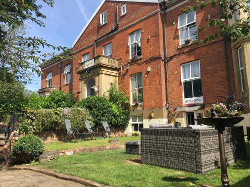 a large brick building with chairs in the yard at Queens Guesthouse Manchester in Manchester