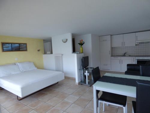 Cet appartement comprend une chambre avec un lit et une table ainsi qu'une cuisine. dans l'établissement Casa Conti al Lago, à Ronco sopra Ascona