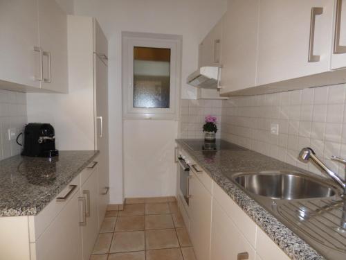 a kitchen with white cabinets and a sink at Casa Conti al Lago in Ronco sopra Ascona