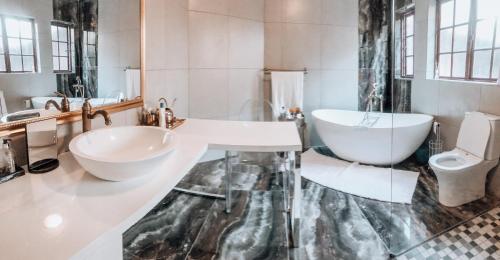 ein Badezimmer mit einem Waschbecken, einer Badewanne und einem WC in der Unterkunft Gold Pot Stay a 5 bedroom House in Pretoria