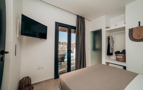 um quarto com uma cama e uma televisão na parede em Ble Kythnos Suites em Episkopí