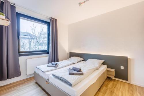 a bed in a room with a large window at Glück Auf Appartements Düppelstraße in Oberhausen